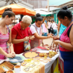 Grupo de turistas interagindo com artesãos locais em um mercado de rua